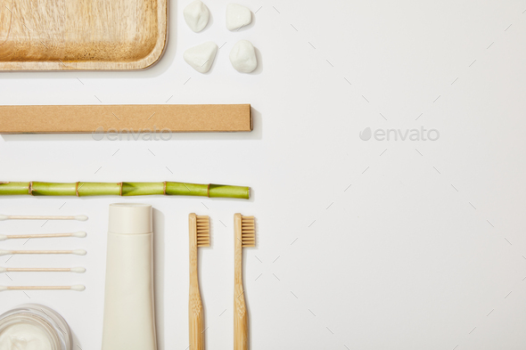 top view of bamboo toothbrushes, toothpaste in tube, cosmetic cream, stones, ear sticks and bamboo