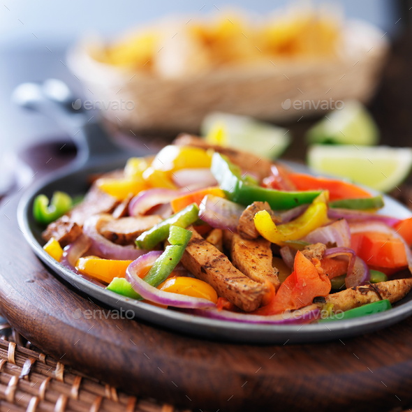 mexican chicken fajitas in iron skillet with peppers Stock Photo by