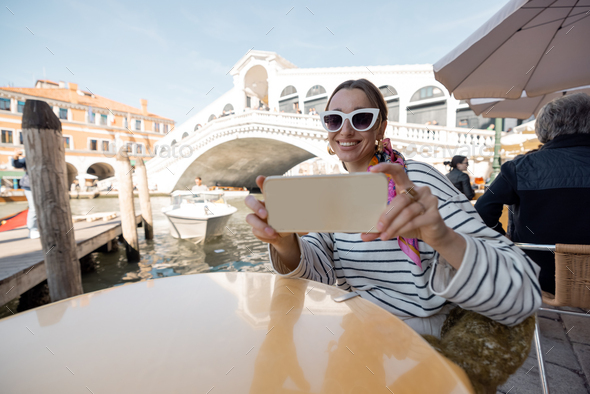 Woman taking selfie at outdoor cafe in Venice, Italy