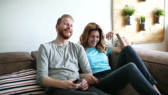 Happy Romantic Couple Smiling Having Fun and Watching Tv