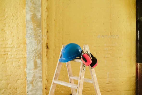 ladder, blue protective helmet and ear defenders at construction site. Home improvement, renovation