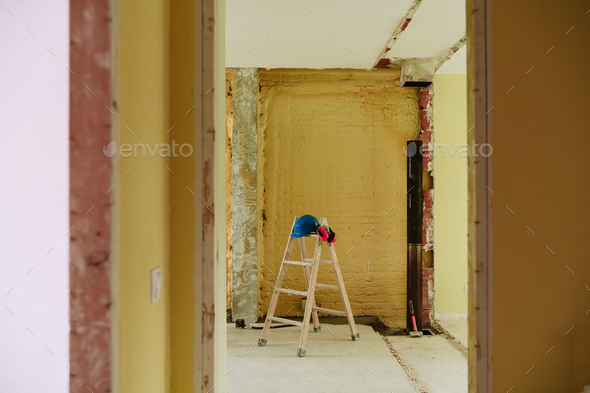 ladder, blue protective helmet and ear defenders at construction site. Home improvement, renovation