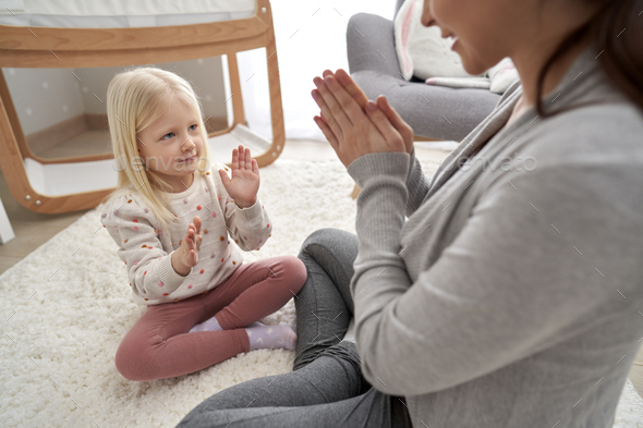Caucasian woman in advanced pregnancy playing hand-clapping game with her elementary age daughter
