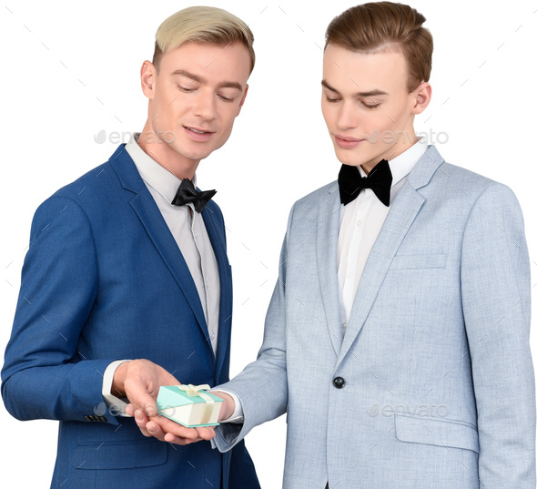 two models in blue tuxedos looking at a tiny gift in a box - Stock Photo - Images