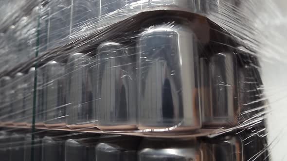 Stock of aluminum cans for cold beverages packed on pallet rack in warehouse alt