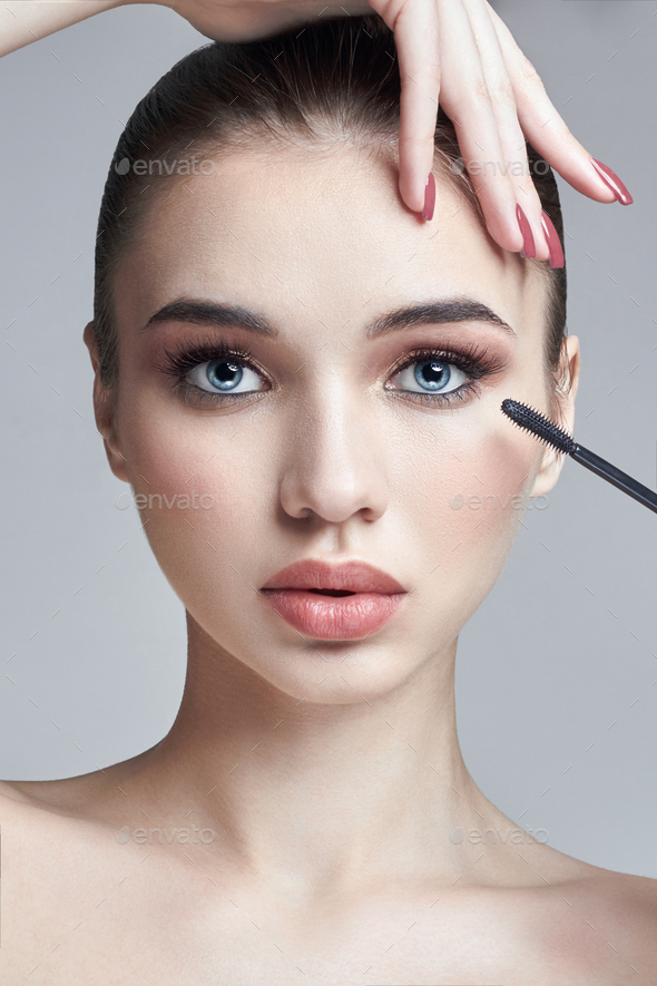 Woman paints eyelashes brush for the eyelashes. The increase in volume of eyelashes, cosmetics for