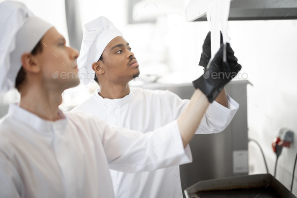 Chefs look on printed checks with orders while cooking in the professional kitchen