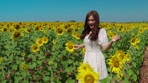cheerful woman walking and enjoying with sunflower field