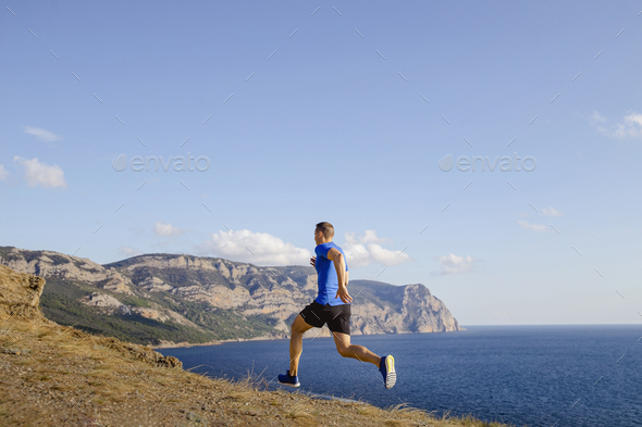 male athlete running uphill trail on sky and sea background - Stock Photo - Images