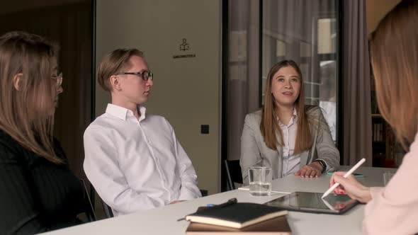 Diverse group of four talented young business people chatting about team building, new projects alt