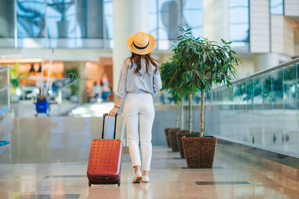 Young woman in hat with baggage in international airport