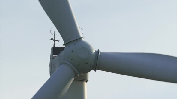 Motion the Blades of a Large Wind Turbine in a Field Against a Background of Orange Sunset on the alt
