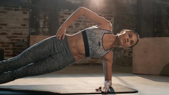 Fitness woman doing side plank exercise workout in gym indoors alt