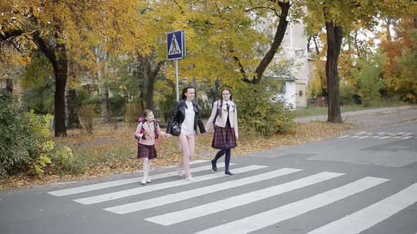 Mother with Her Daughters are Going to School Cross the Road at a Pedestrian Crossing