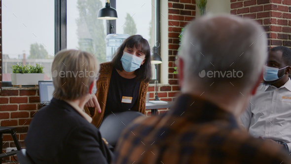 Desperate woman with face mask explaining anger management issues to therapist at aa meeting