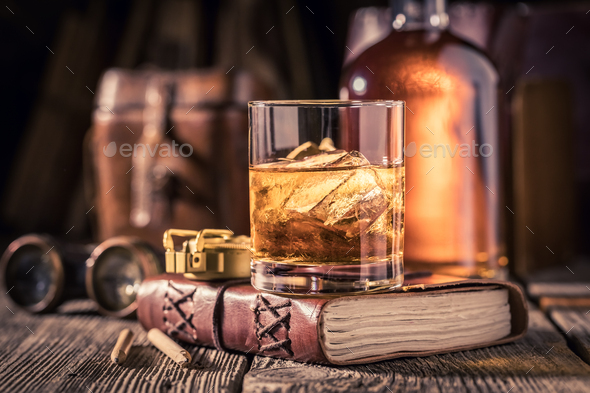 Closeup of whisky with ice on old journal