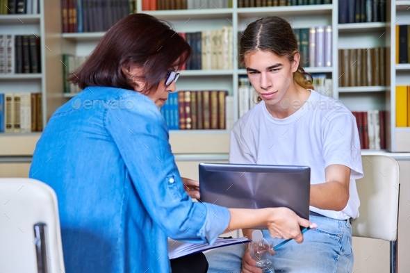 Woman school psychologist talking and helping student, teenage male