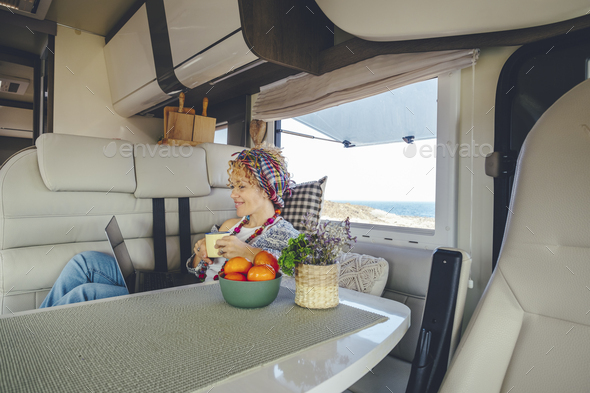 One woman using laptop inside a modern camper van. Van life and digital nomad remote worker