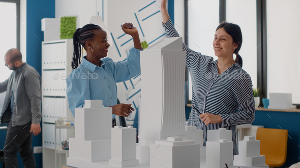 Team of women giving highfive after architecture work progress with building model