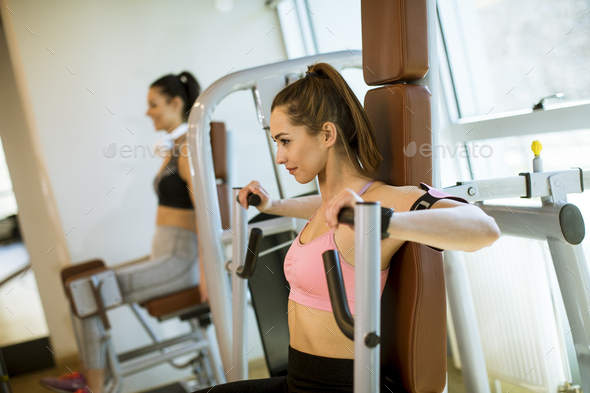 Young determined fitness woman doing exercises at chest press machine at modern gym