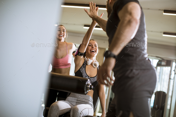 Young woman having exercises on leg extension and leg curl machine in the gym