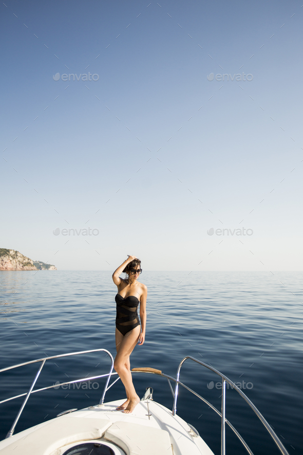 Attractive woman wearing glasses and white clothes poses sitting on a yacht  on the background of