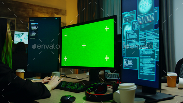Zoom in shot of hacker girl in front of computer with green screen
