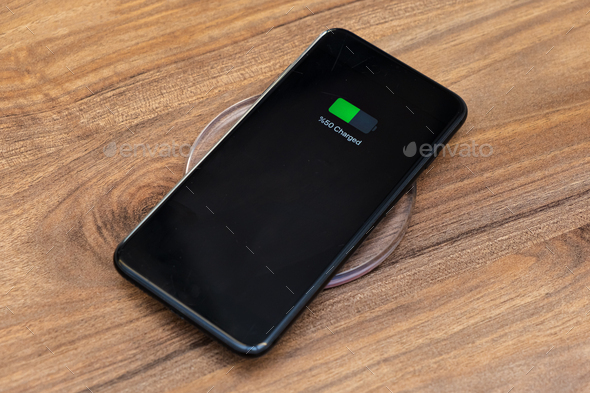 smartphone battery charging showing half charged battery on fast wireless charger concept - Stock Photo - Images