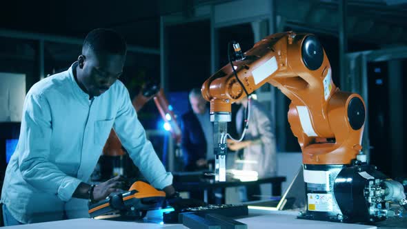 African Scientist Is Operating a Robotic Arm alt