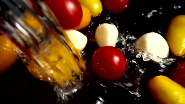 Falling red and yellow cherry tomato and garlic into water alt