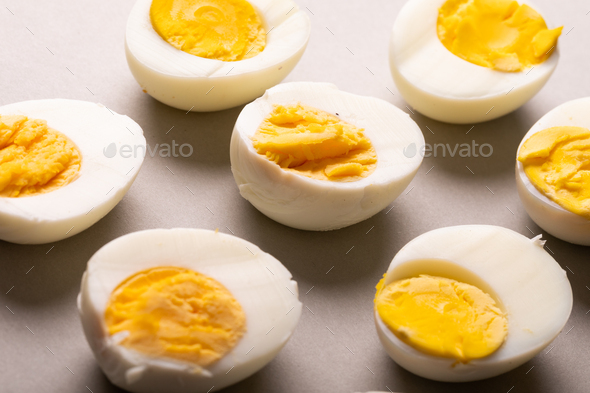 High angle close-up of fresh white boiled eggs with yellow yolks on gray table
