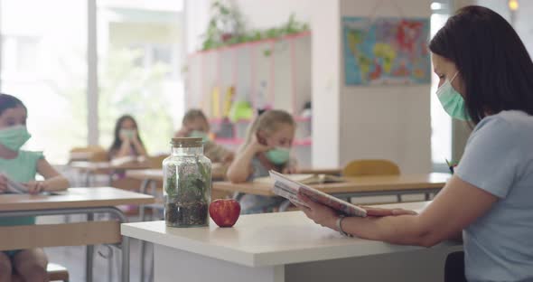 Children in the Classroom at School in Masks Sit in the Classroom and Listening the Teacher alt