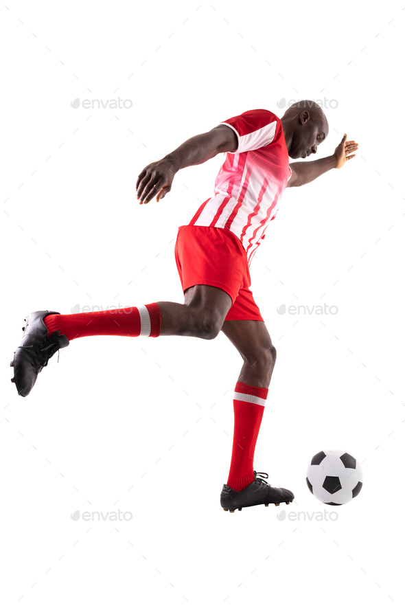 Side view of young male african american soccer player kicking ball over white background