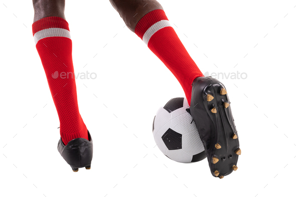 Low section of young male african american soccer player kicking ball over white background