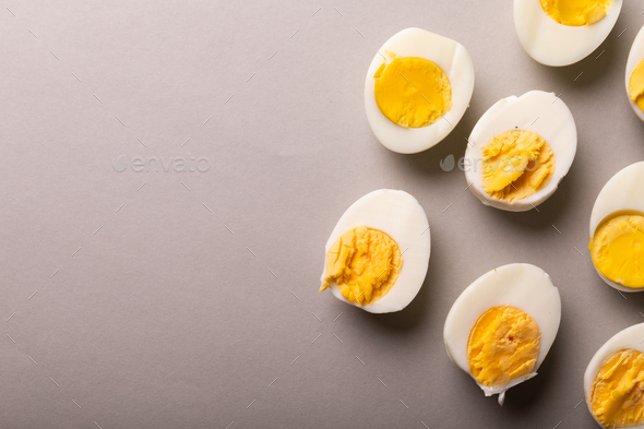 Directly above view of fresh white eggs boiled with yellow yolks by copy space on gray background