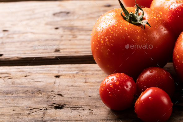 Close-up of fresh red tomatoes with water drops on wooden table - Stock Photo - Images