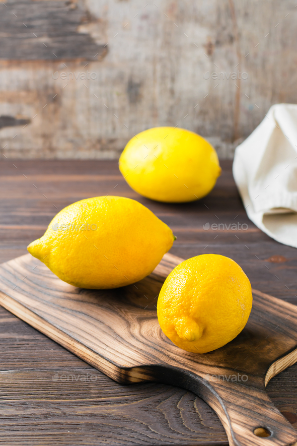 Whole ripe lemons on a wooden cutting board on the table. Organic nutrition, source of vitamins