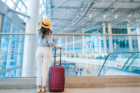 Young woman in hat with baggage in international airport