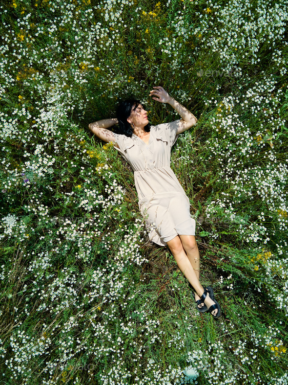 Drone aerial view of relax woman in dress lying on flower blooming meadow