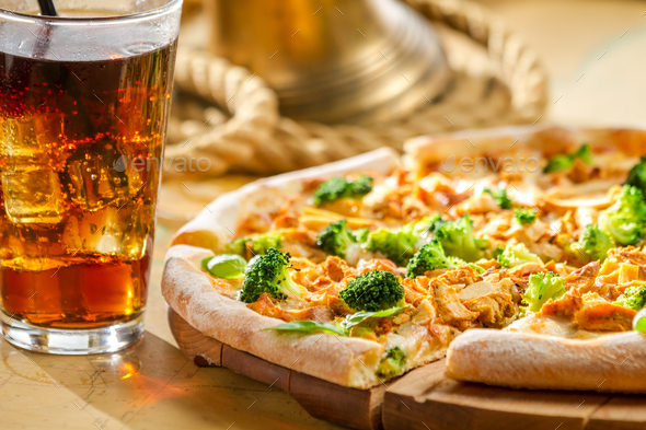 Fresh pizza made of broccoli, chicken and basil served with cold cola