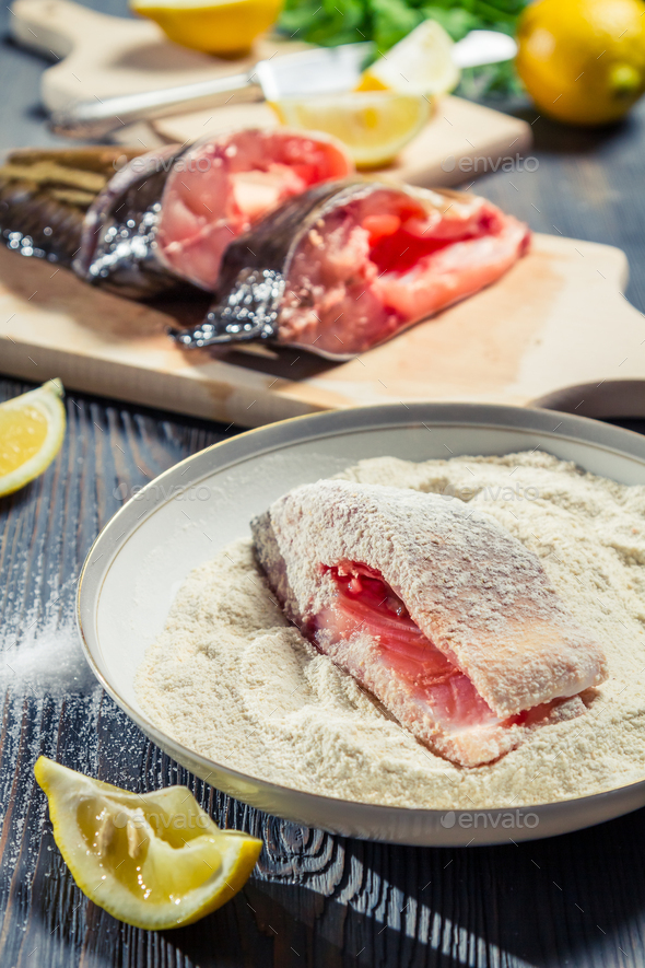 Fish in the seasoned flour for frying lemon on a plate Stock Photo by