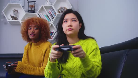 Cheerful Happy Attractive Girls Playing Video Games at Home. Focused Asian Woman Losing the Game alt