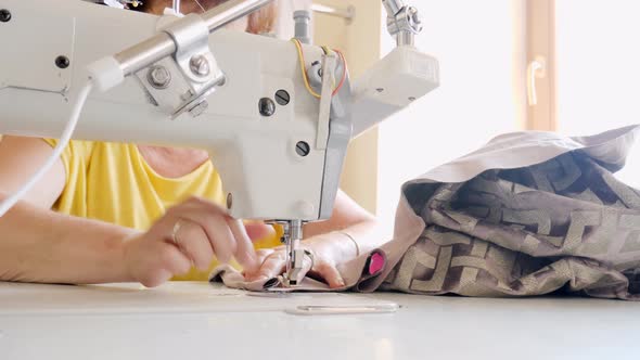 Unrecognizable Elderly Needlewoman Sewing Curtains Using Stitching Machine