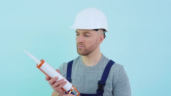 Handyman in Overalls Holding Silicone Adhesive alt