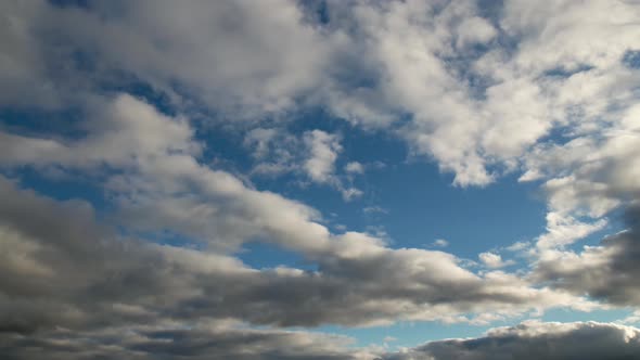Layered Cumulus Clouds Floating Across the Blue Sky in the Evening alt