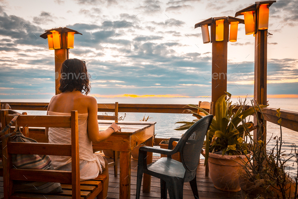 A young woman in a West End restaurant on Roatan Island in a sunset