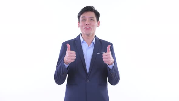 Happy Young Asian Businessman Giving Thumbs Up and Looking Excited alt