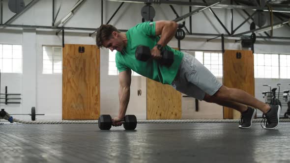 Side view athletic Caucasian man lifting alternate weights alt