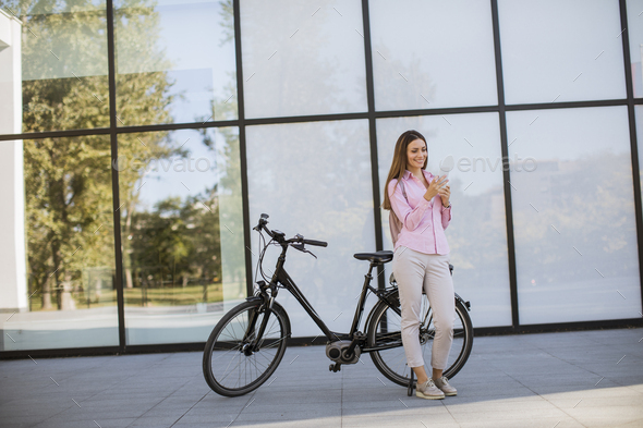 woman using mobile phone by modern city electric e-bike