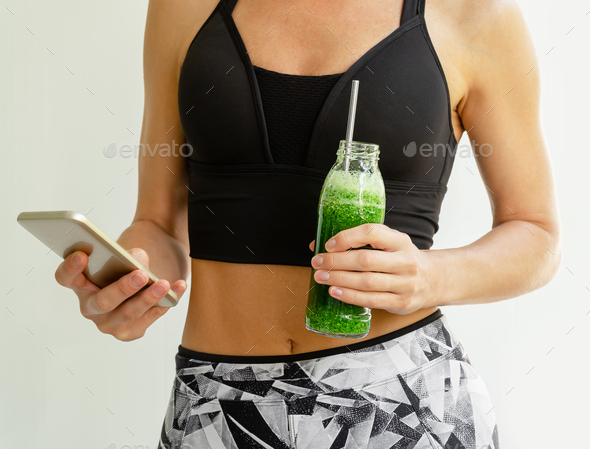 Calorie counting application. Slim woman holding a bottle of broccoli and spinach smoothie.